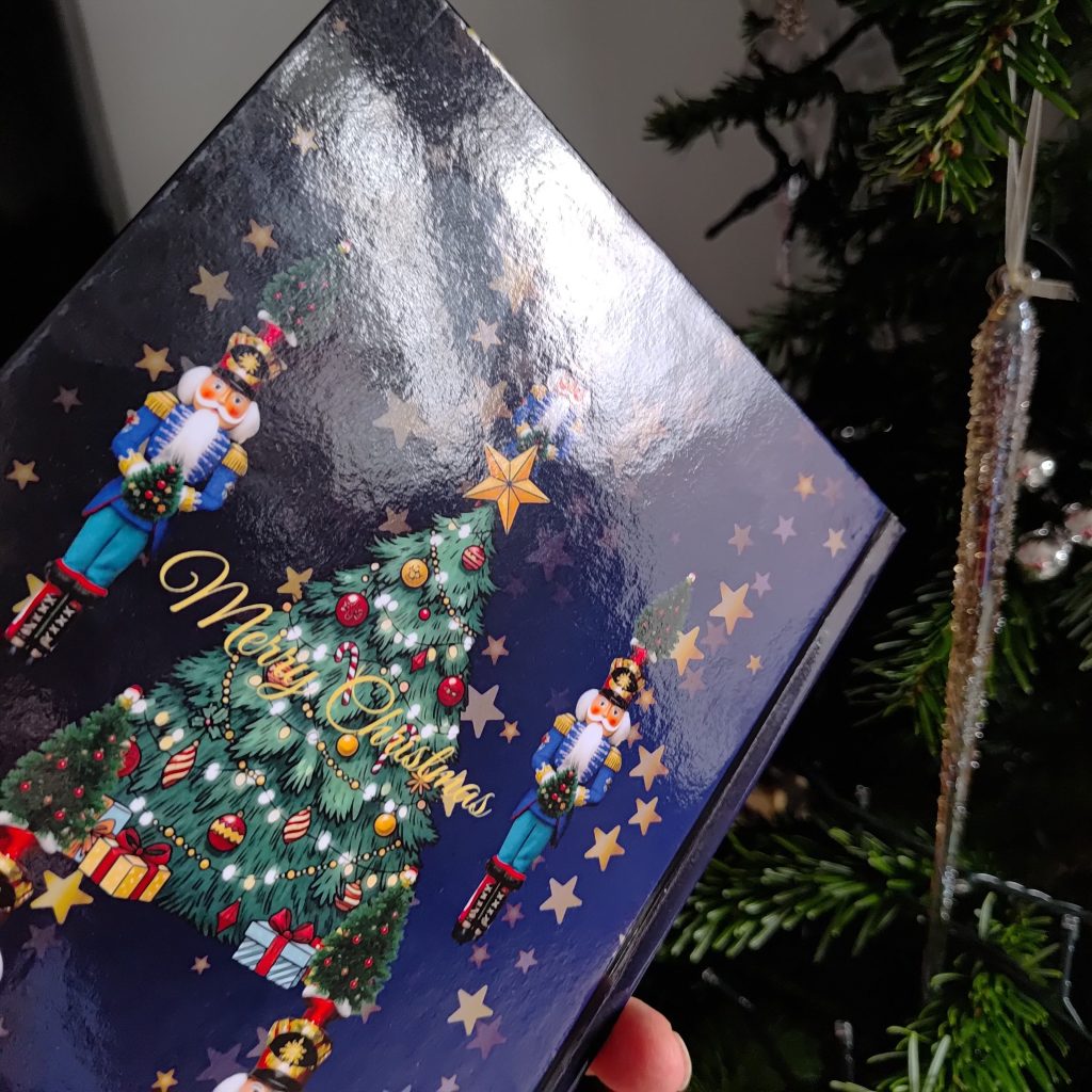 Back cover of Christmas Nutcracker Journal with festive nutcracker soldiers, decorated Christmas tree, golden stars, and Merry Christmas text on a dark blue background