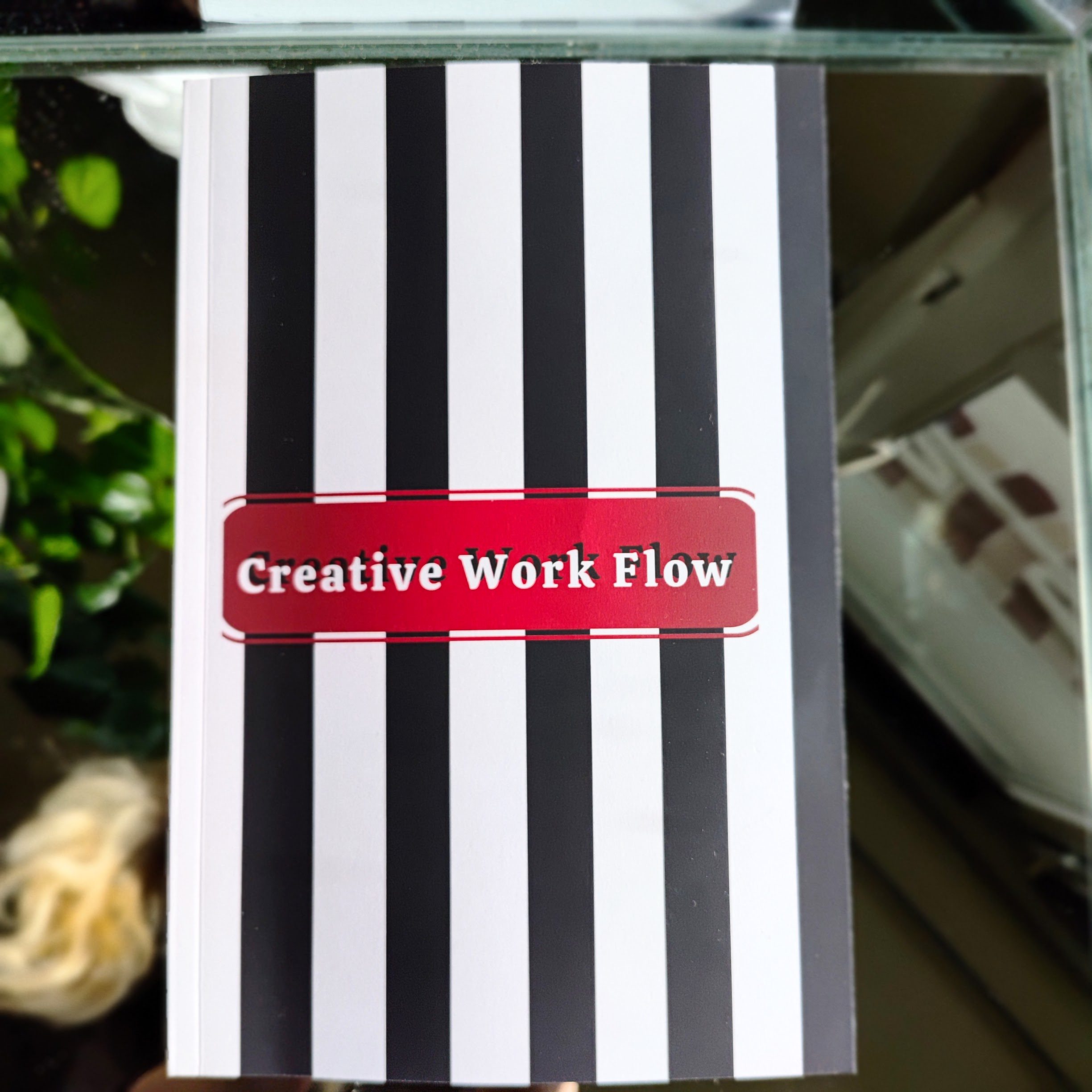 Matte notebook with black and white stripes, red border, and the title Creative Work Flow at the center.